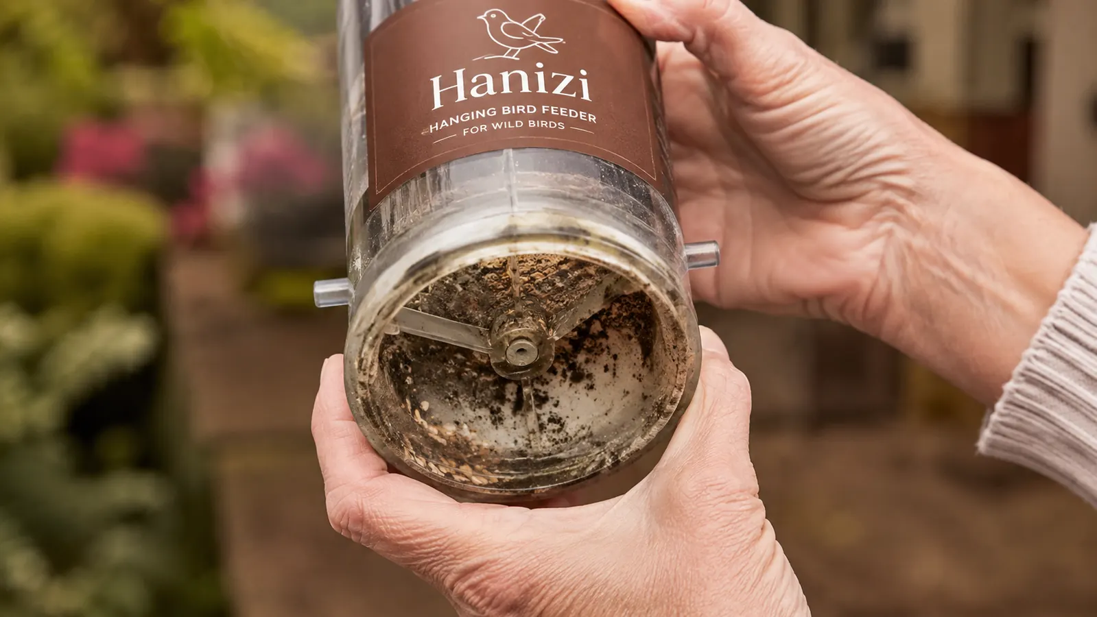 Black mould spots visible inside the transparent tube of a bird feeder, showing a drainage and moisture problem