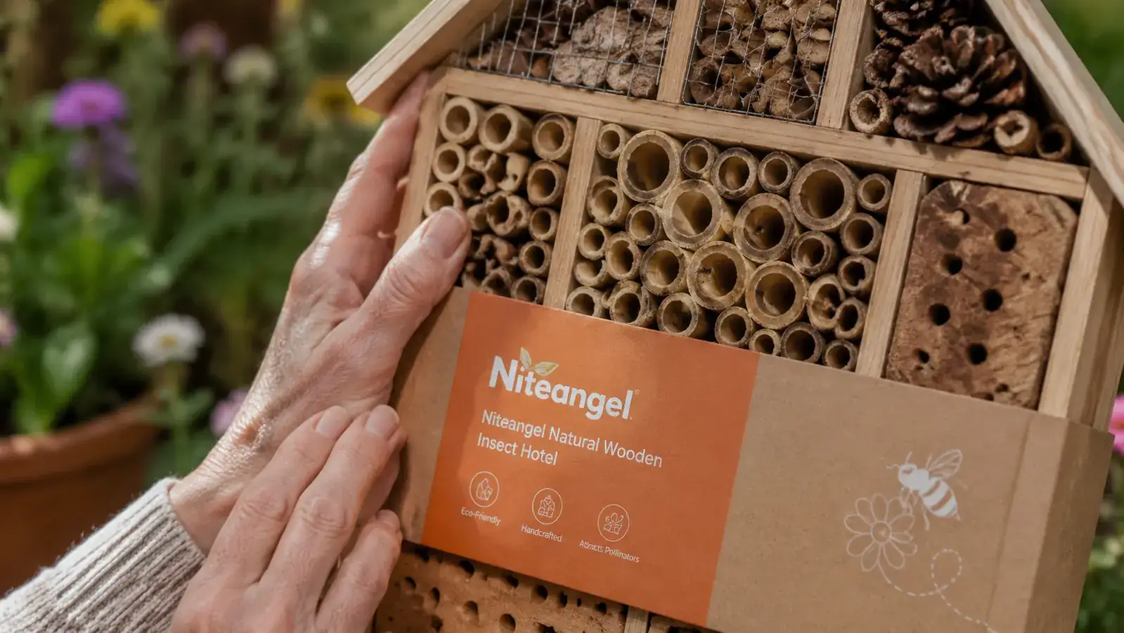 Close-up of the Niteangel insect hotel showing bamboo tubes, pine cones, and bark-filled chambers with a solitary bee entering a tube